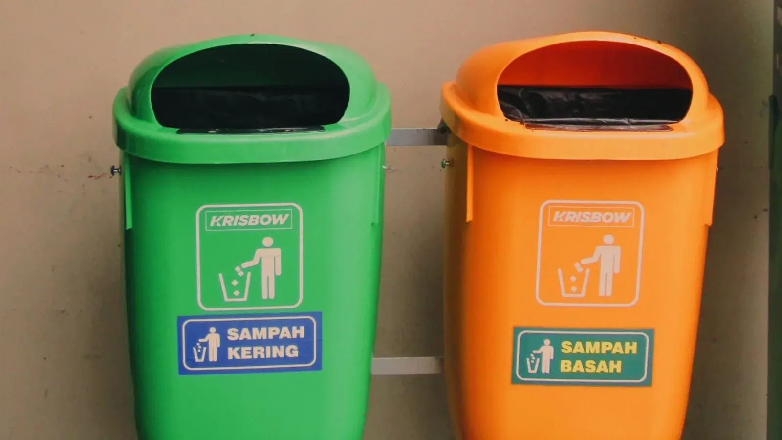 Residents of a Balinese banjar sorting household waste into organic and inorganic bins at a village waste bank, with a TPS3R building in the background