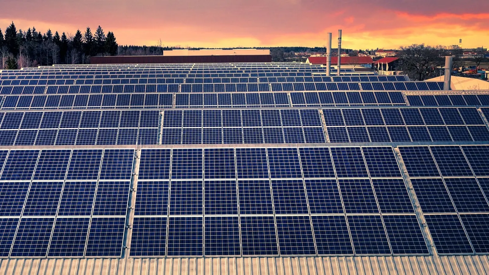 Rooftop solar panels covering the roof of a large manufacturing plant in an Indonesian industrial estate, with warehouses and factory buildings stretching into the distance