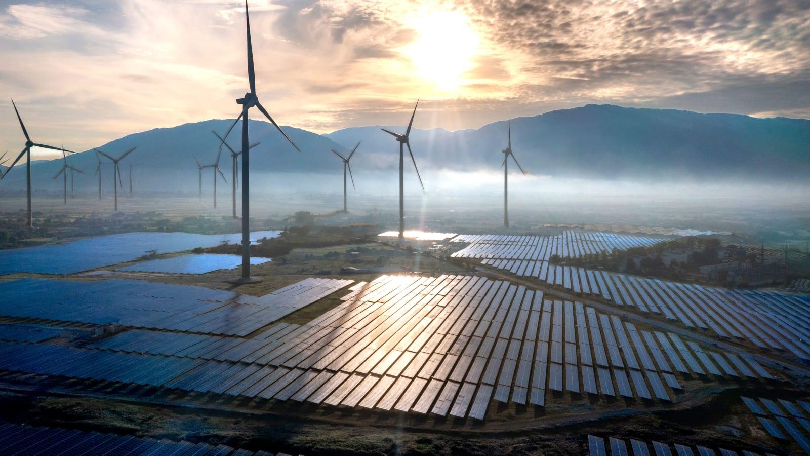 Rows of floating solar panels on a calm Indonesian reservoir with a dam wall and green hills in the background