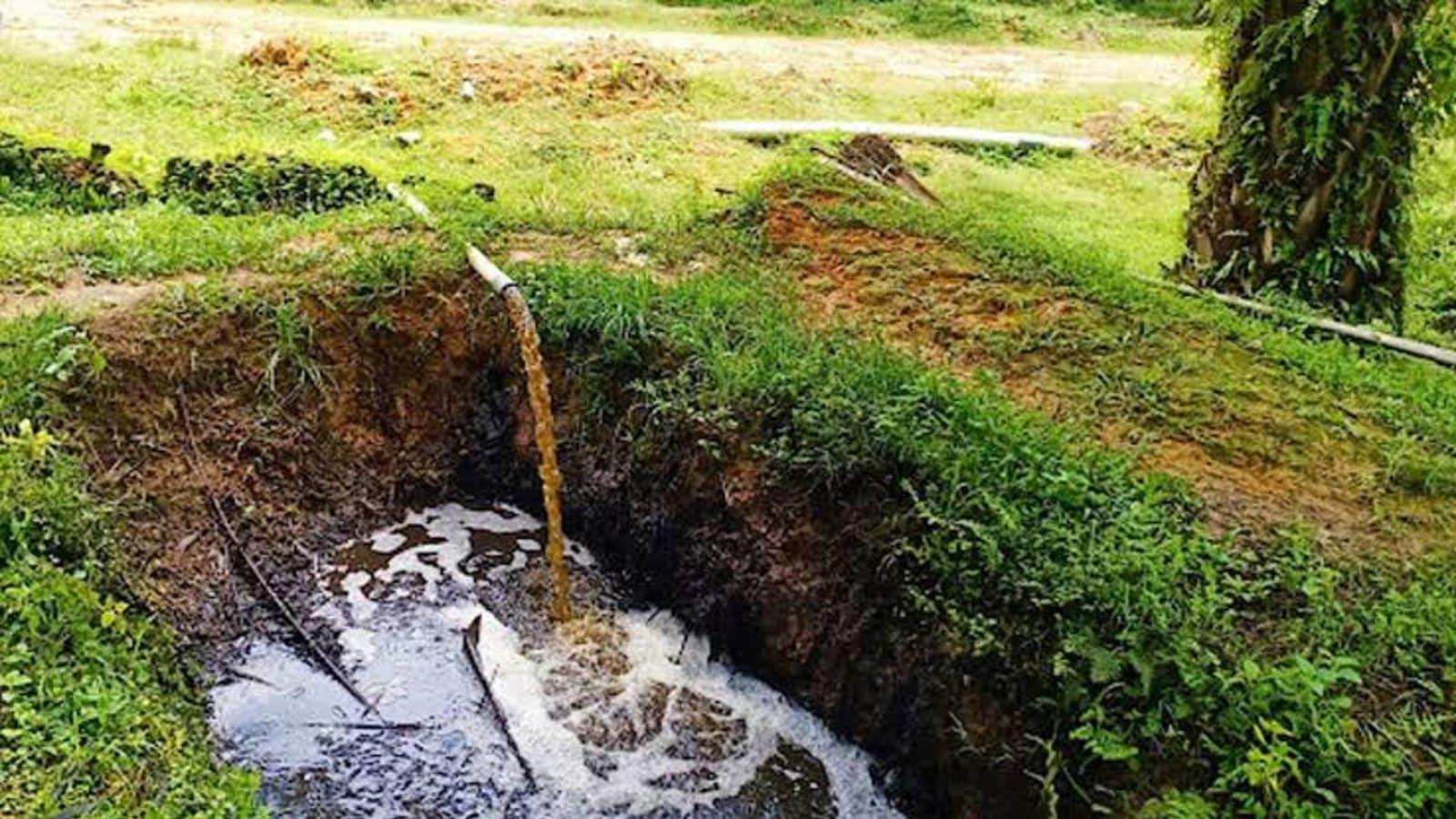 A biogas upgrading unit and covered effluent ponds beside a palm oil mill in South Sumatra, with gas pipework running toward a metering station