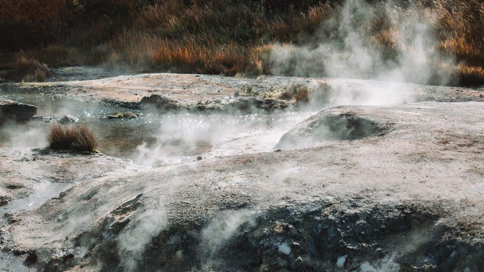 Steam rising from geothermal wellheads and turbine buildings among the forested hills of North Tapanuli, North Sumatra