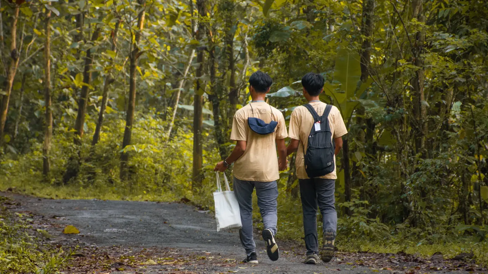 University students in campus jackets helping residents separate organic and inorganic household waste into labelled bins in a Bandung neighbourhood